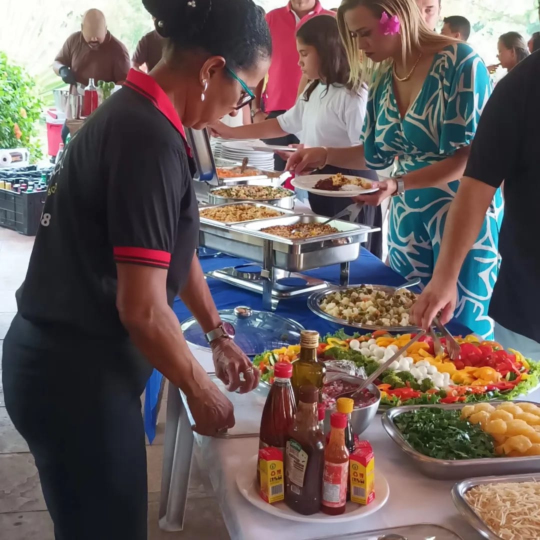 buffet de eventos com funcionárias servindo saladas, comidas em rechauds e convidades se servindo em mesas ao ar livre  