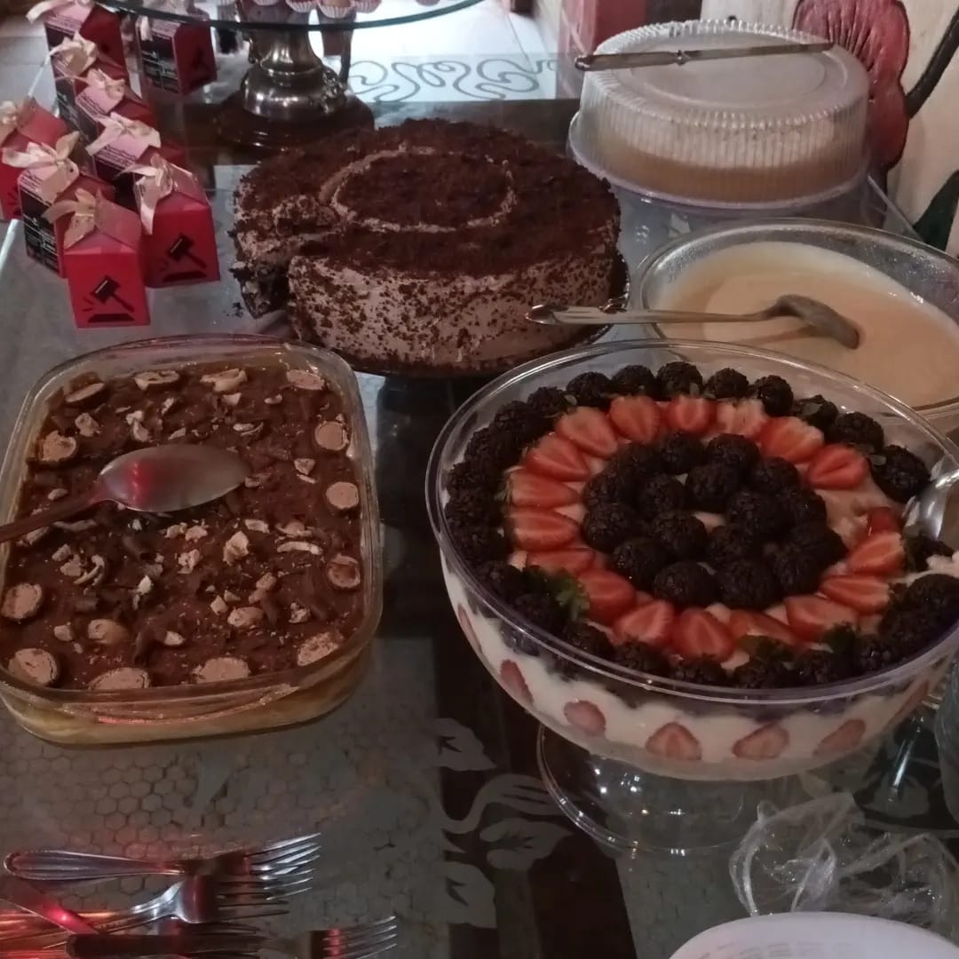 mesa com Various doces e sobremesas: pavê de morango com brigadeiro, bolo de chocolate, torta e caixinhas de l